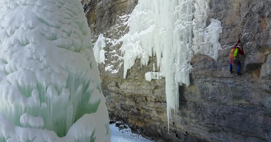 A person in climbing gear climbs up a sheer cliff