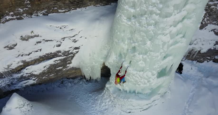 A person climbs up an icy cliffside