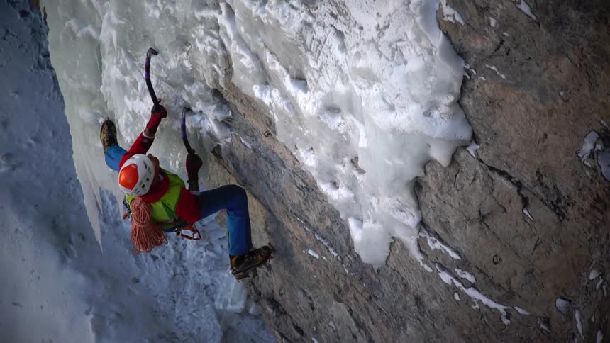 Woman using hooks climbs a snowy mountain