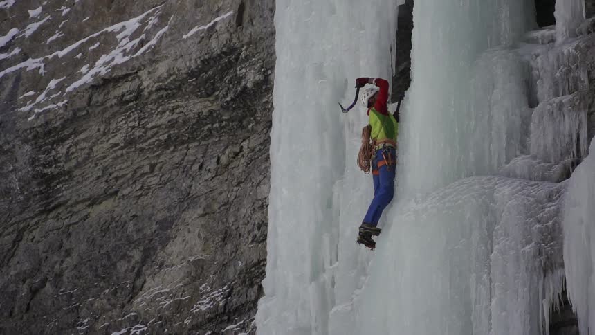 A man climbs up an icy cliffside