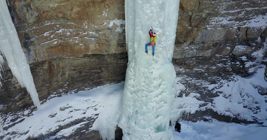A person climbs up an icy cliffside