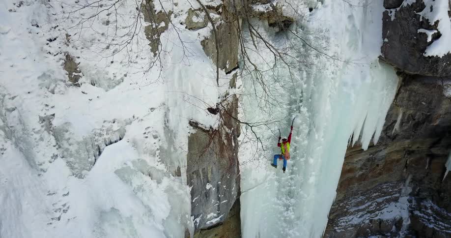 A person climbs up an icy cliffside in the wilderness