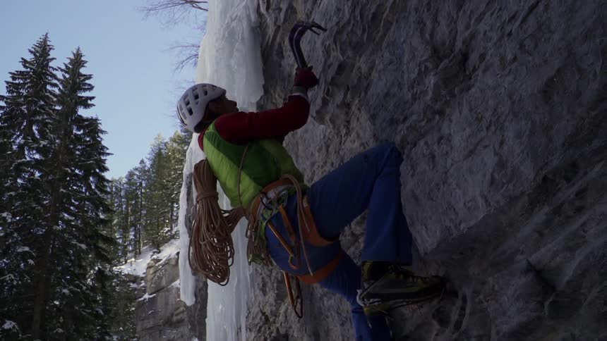 A man in a helmet is climbing up a cliff
