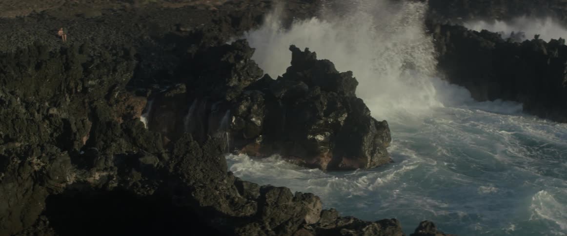 Waves crash onto a jagged rocky shore