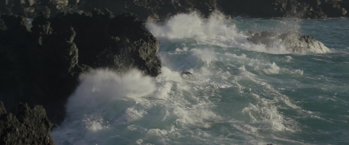 Large waves cover the rocks by the shore