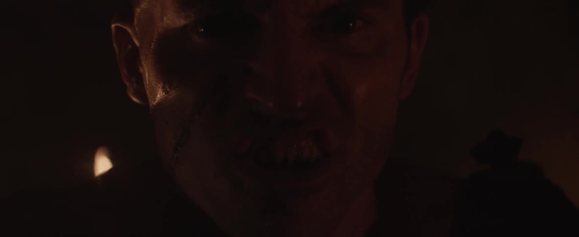 A man with sharp teeth is talking in a cave