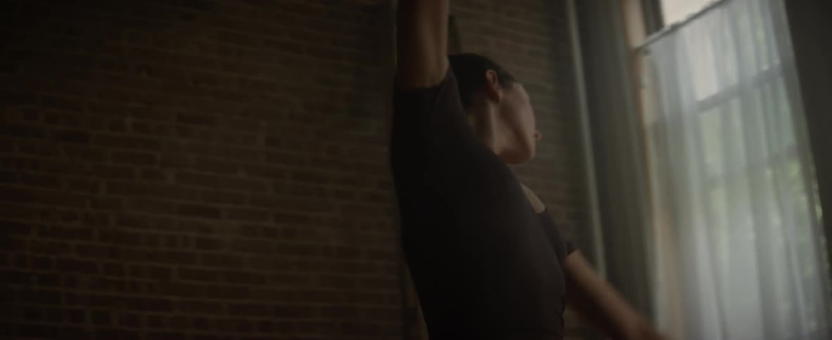 A woman is ballet dancing by a window