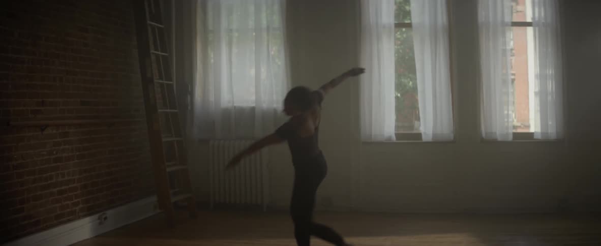 A ballerina is dancing inside a dance studio