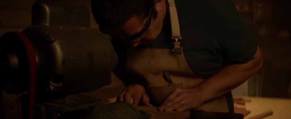 A man is cutting a piece of word on a machine