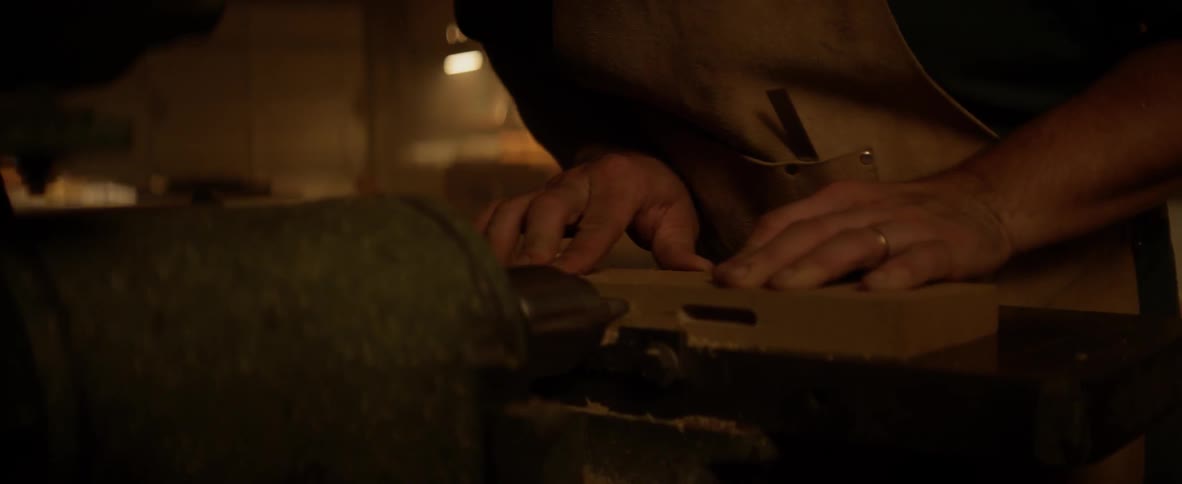 A man is working in a shop carving wood