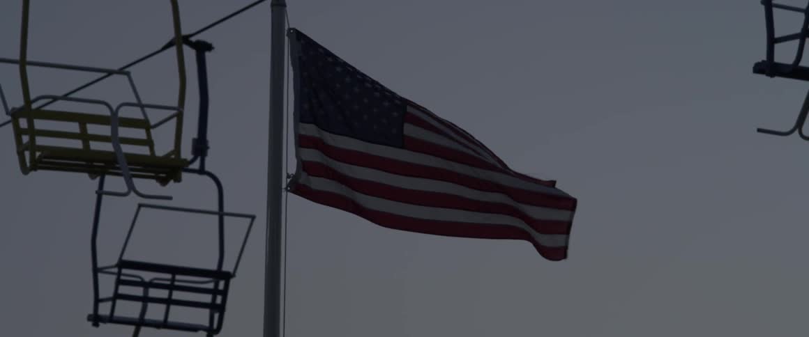 An american flag flies as a ski lift passes