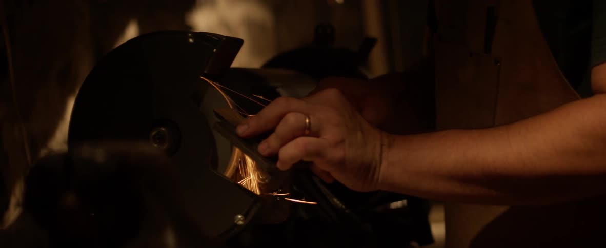 Man using a grinding machine to hone something in a dark area