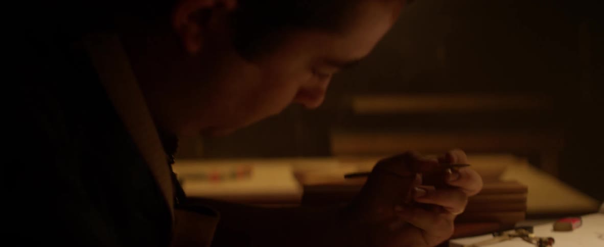 Man writes in a notebook on a desk in a dimly lit room