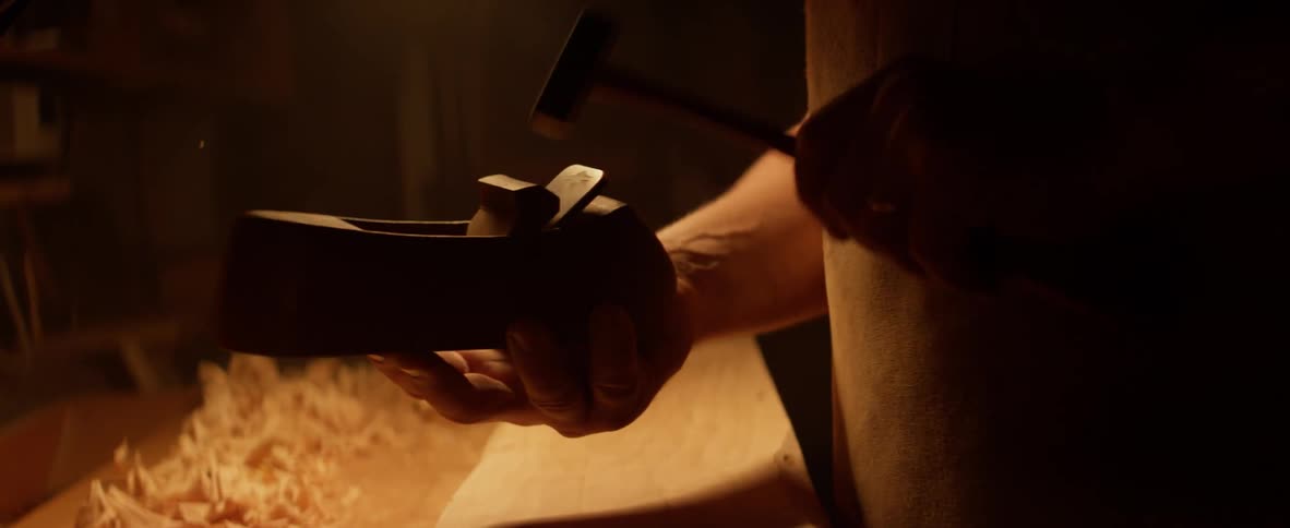 Man tapping a hand plane wood scraper with small hammer