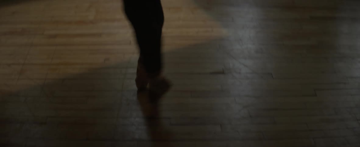 A ballerina dances across a wood floor