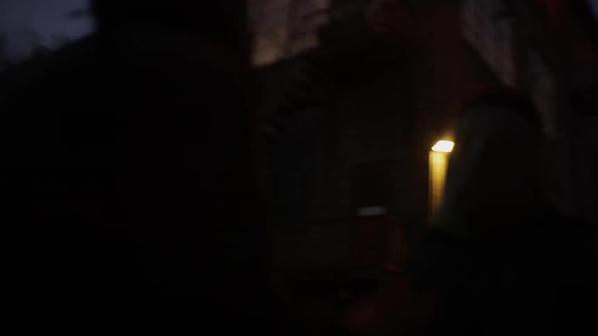 A group of people run down an alley under a red flare