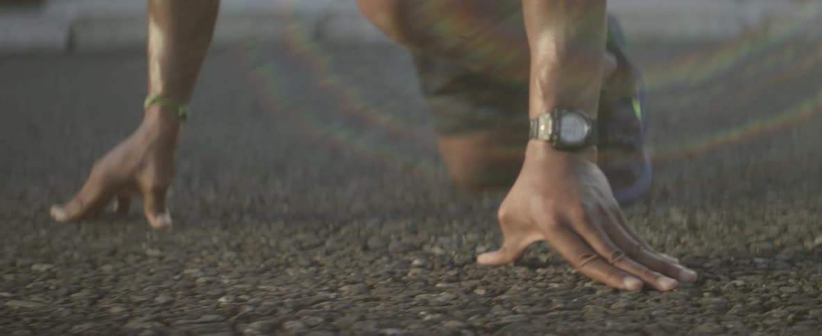 Man wearing a watch is in a crouched position on the ground