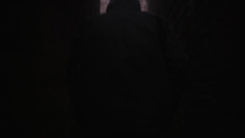Person walks down a dark hallway out into the woods