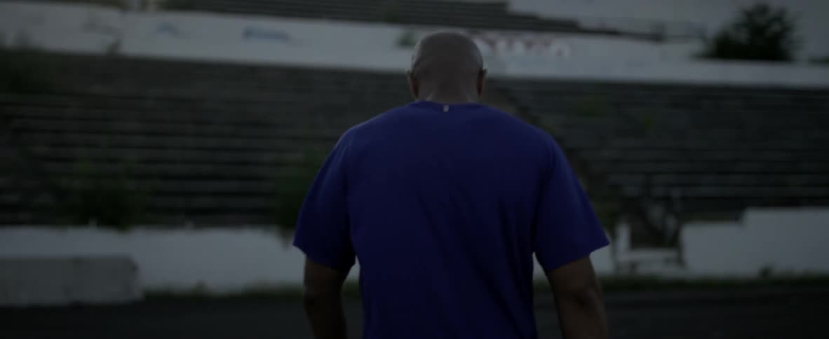 A man walks along the field on a cloudy day