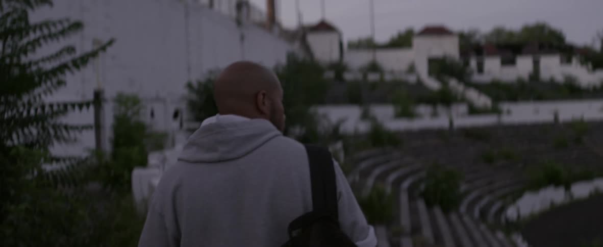 A man with a backpack walks across bleachers