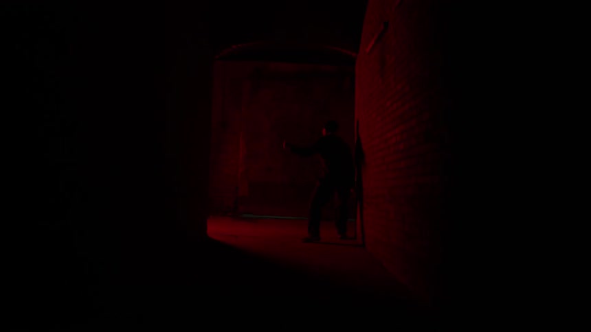 A person is chased down a very dark alley