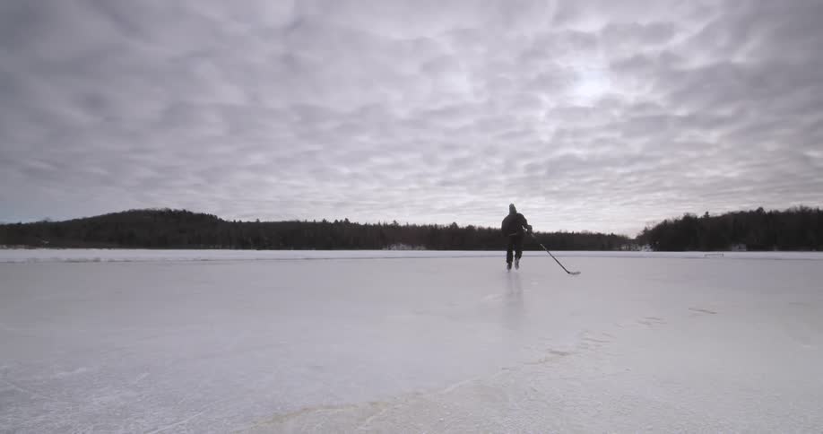 Man skating across ice holding a hockey stick