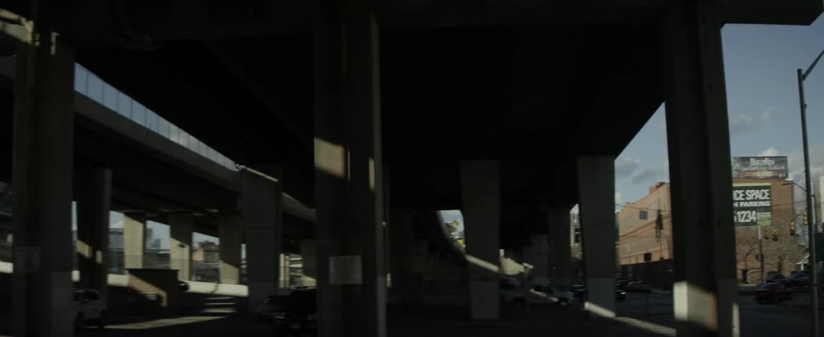 Billboards are on top of the buildings past the overpass
