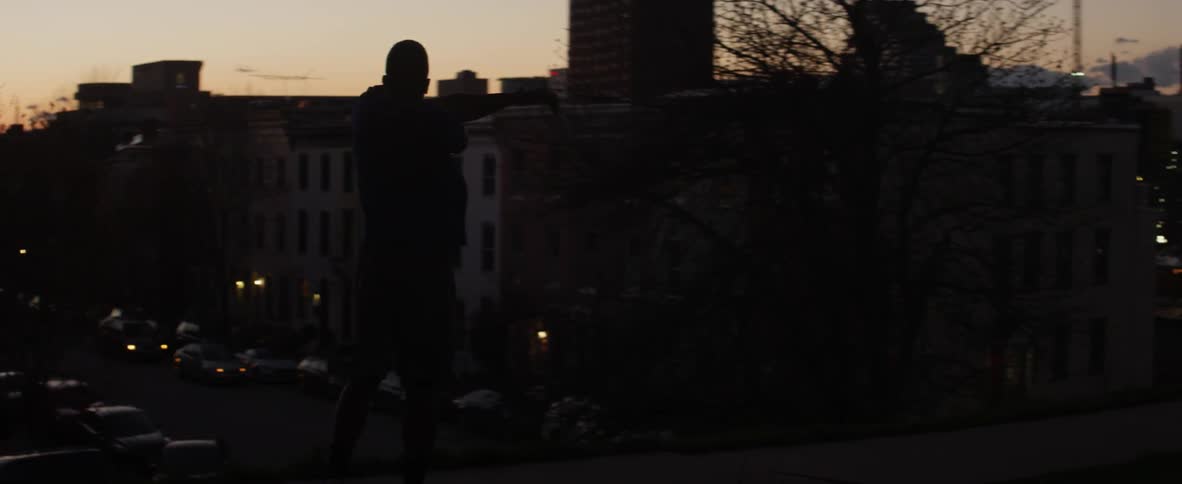 An athlete stretches and warms up at dusk in a city