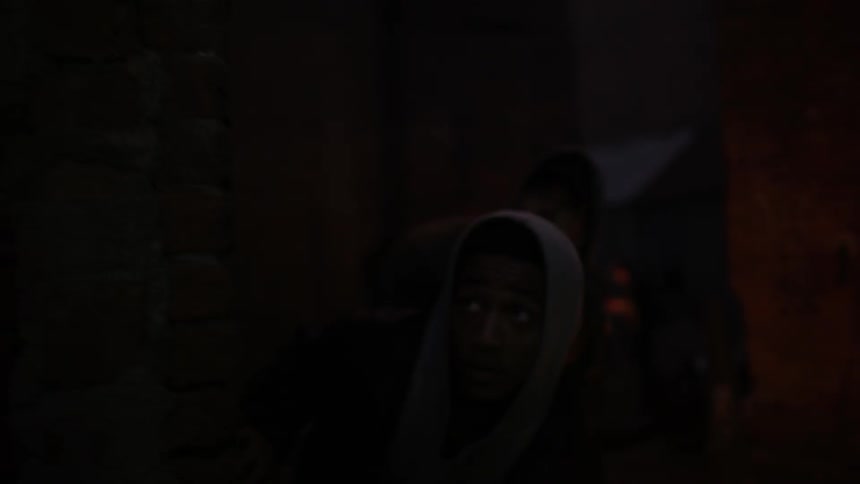 Two men peek around a corner before moving