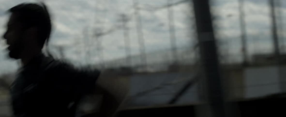 A man runs by a chain link fence