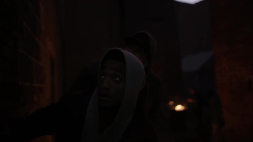 Two men sneak around the corner of a building