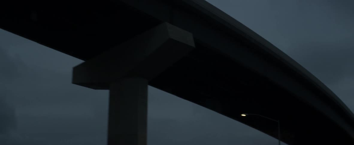 A vehicle drives beneath an overpass at night