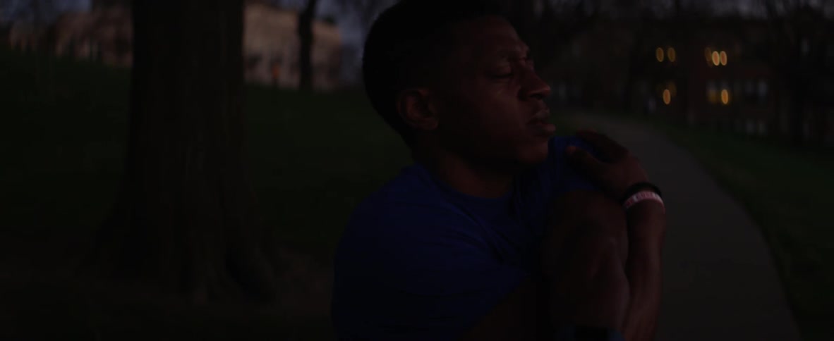 A man stretches while standing outside at night