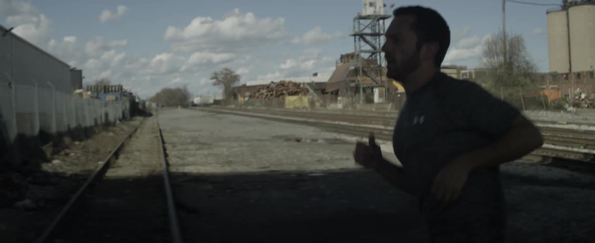 Bearded man jogging over train tracks