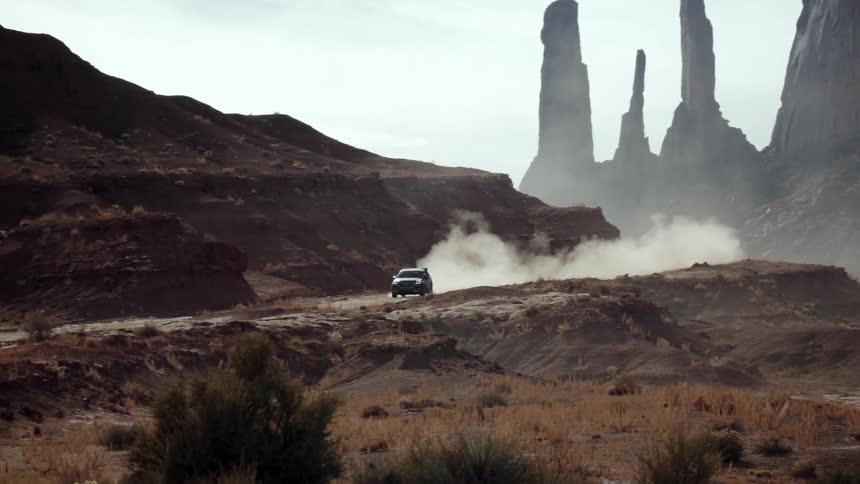 A vehicle kicks up dust while driving in the desert
