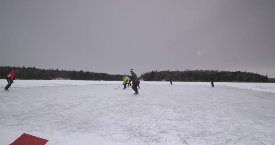 Group of young men playing ice hockey outdoors on a large frozen area