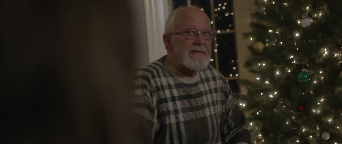 An older man talking by a christmas tree