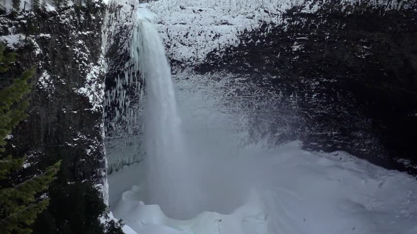 Waterfall splashes into a pit of snow