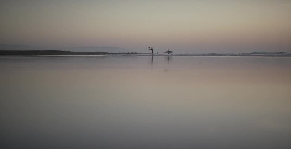 Two people stand at the edge of a body of water