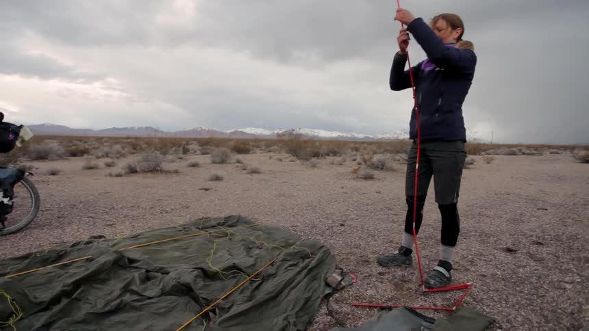 A woman is setting up the sticks for a tent