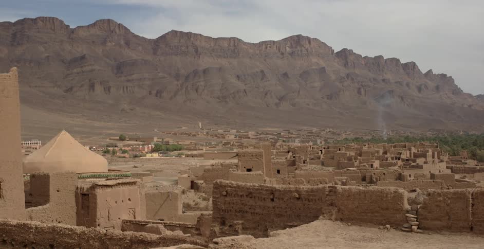 Stone buildings sit in front of a mountain