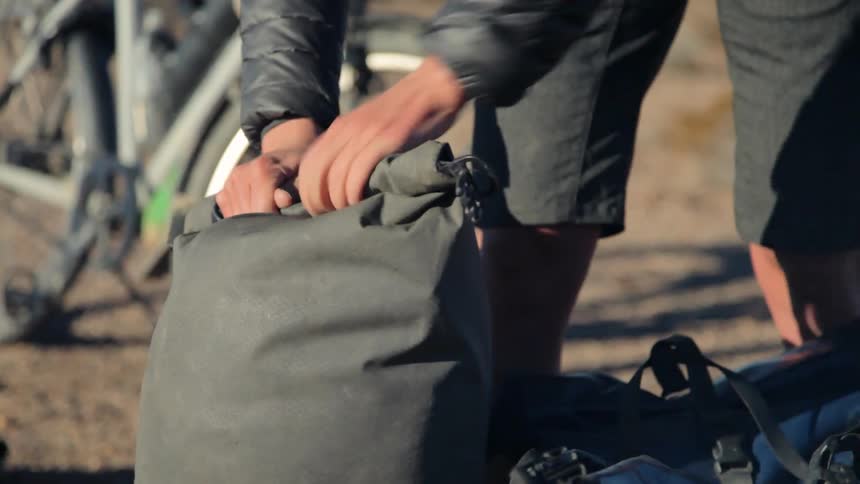 Woman wearing shorts secures a duffel bag