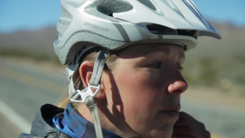 A woman puts on her bicycle helmet