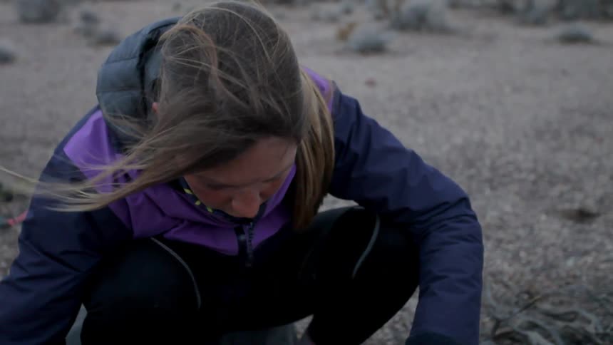 A woman is building a campfire on a windy day