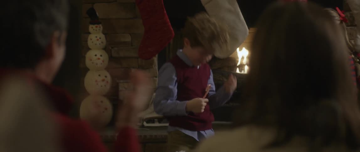 Young boy entertaining his enthusiastic crowd like a rock star in front of the fireplace