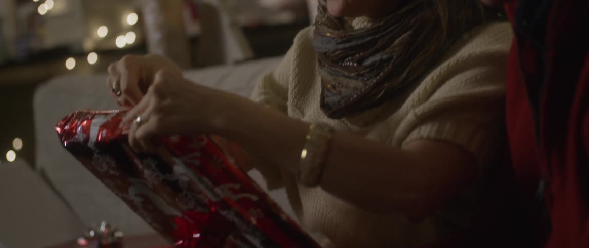 Two people are talking and laughing as they wrap a christmas present