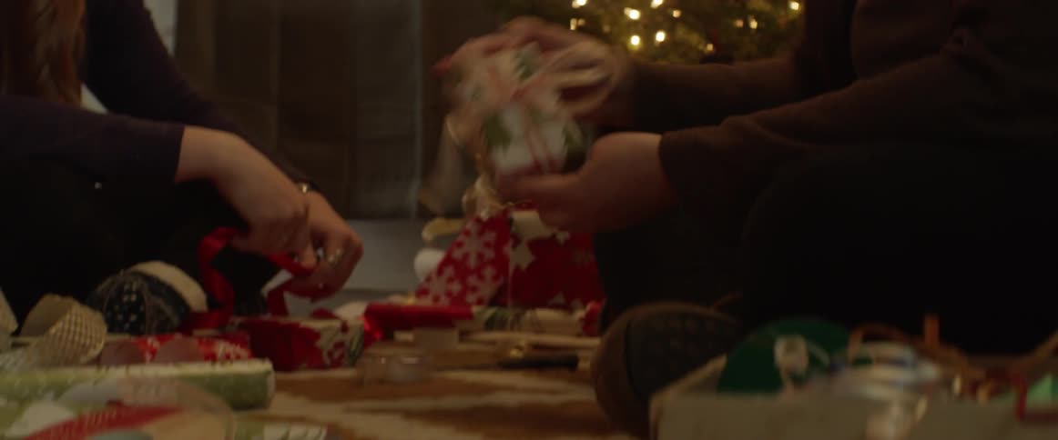 Two people wrap christmas gifts together