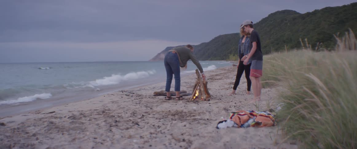 Women and boy start a campfire on the beach