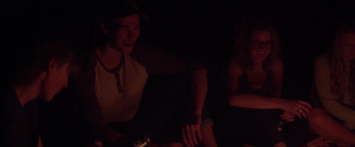 People sitting outside by firelight at night