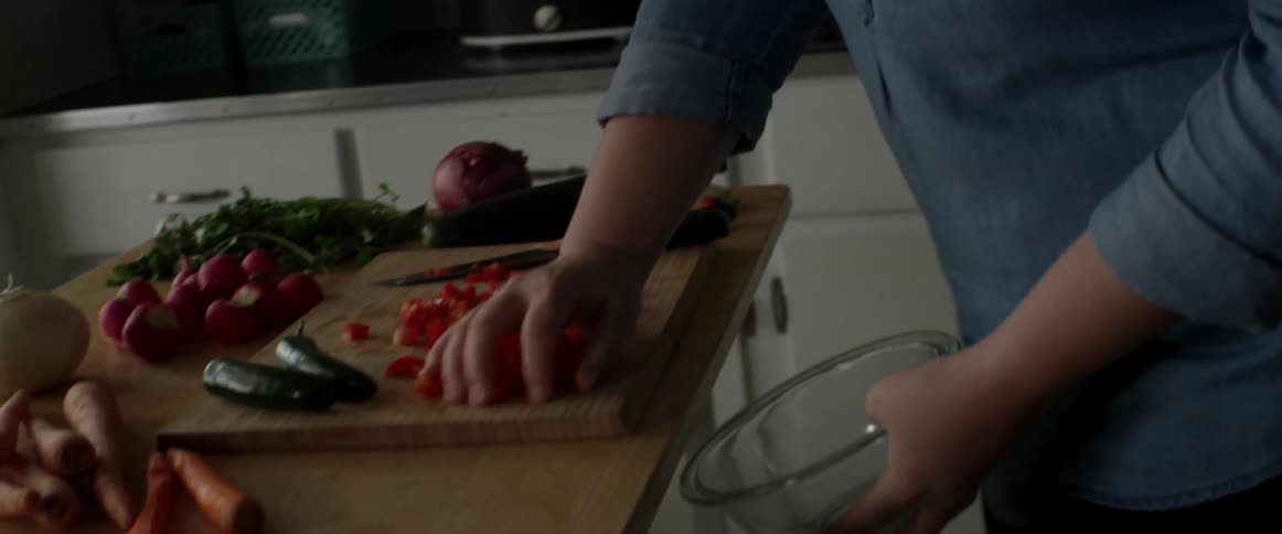 A woman is putting food in a bowl in the kitchen